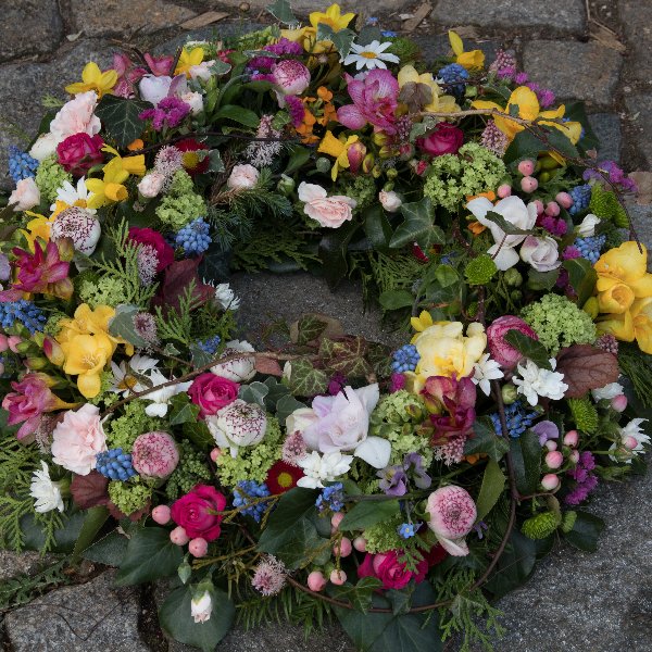 Trauerkranz rundgesteckt mit Frühlingsblüten, Rosen und Nelken Bild 1